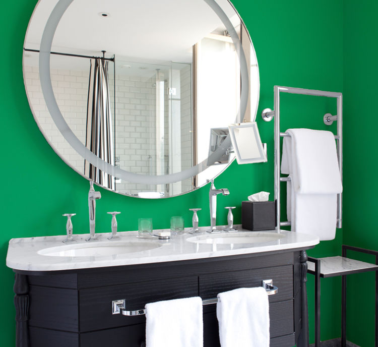 bathroom double lavatory with black wooden cabinets, sharp green walls, rounded mirror