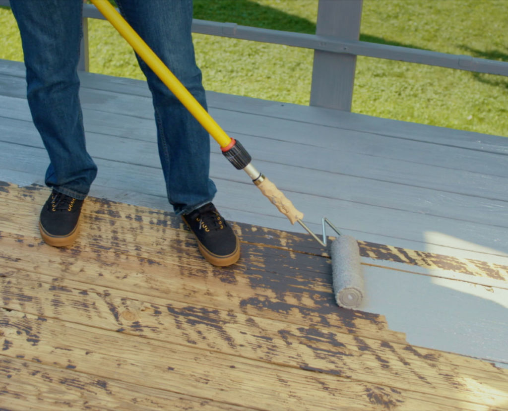 man applying stain remover on wooden deck floor