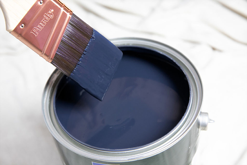 can of blue paint with paint brush