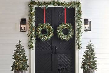 bright white entryway with dark doors and lit-up holiday greenery