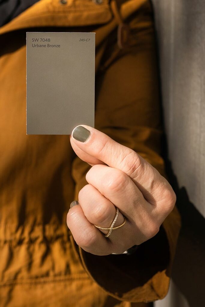 a closeup of a woman holding a color chip for Urbane Bronze