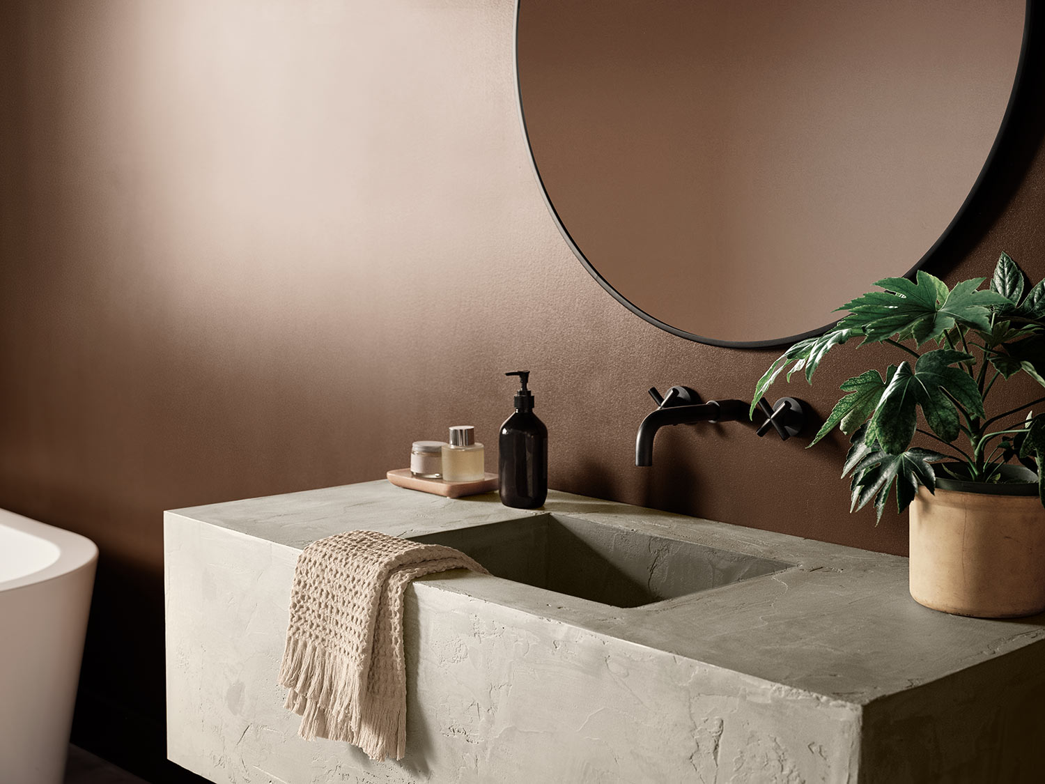Bathroom with modern concrete block sink with a plant, circular mirror and walls painted Java SW 6090
