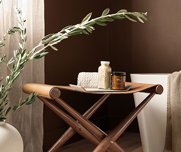 Close up of leather folding stool with bath products on top in Java SW 6090 bathroom