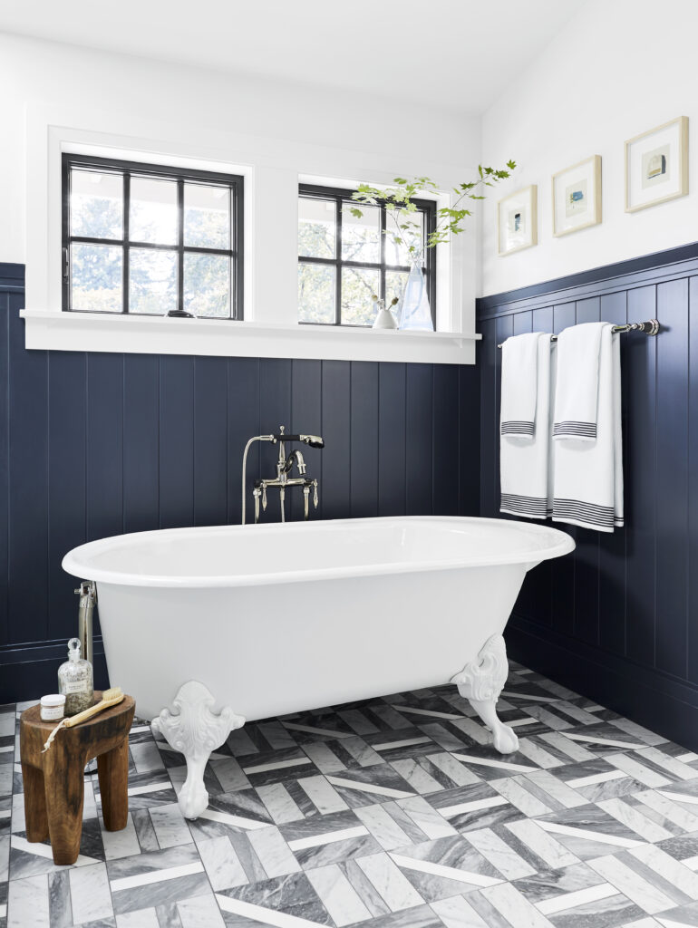 An airy bathroom with a clawfoot tub and wainscotting painted in Cyberspace SW 7076.