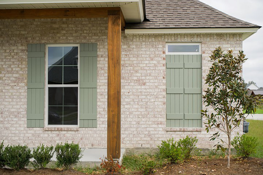 Exterior of a brick home with shutters painted in Evergreen Fog from Sherwin-Williams.