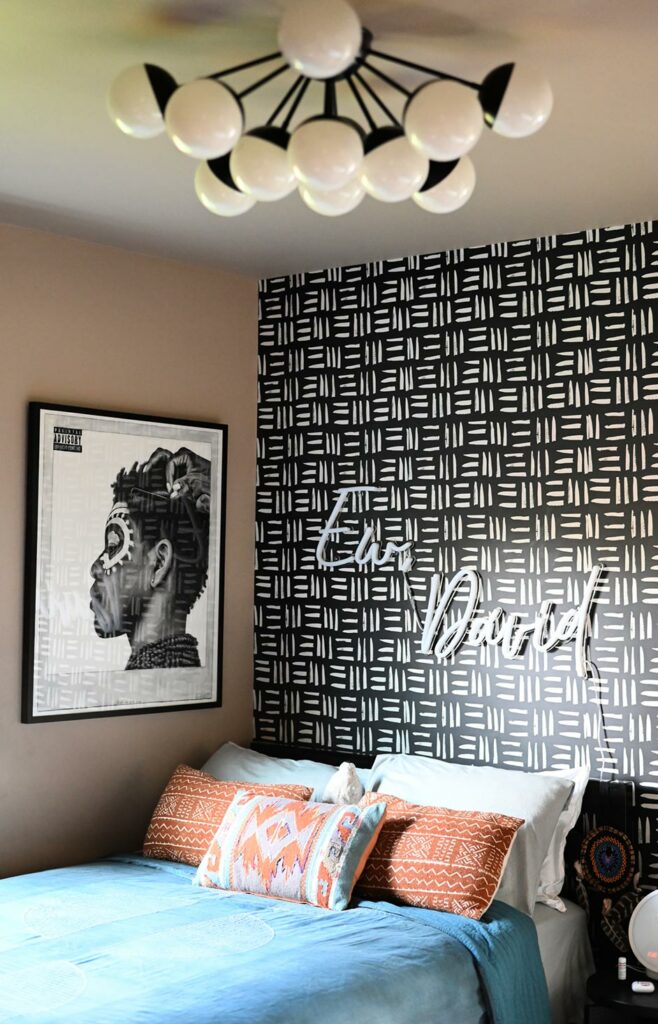 a bedroom with black and white patterned walls and a neon sign