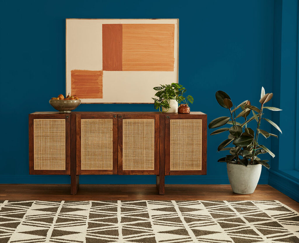 vignette of a console and wall art against blue walls