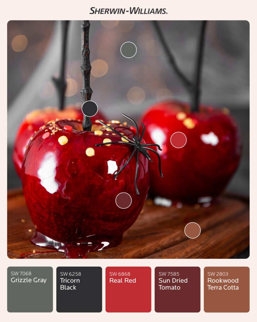 Photo of three candied apples on a wood serving platter. One apple has a fake spider climbing up the side. Round color dots over the photo correlate to Sherwin-Williams paint swatches below the image. Colors include Grizzle Gray SW 7068, Tricorn Black SW 6258, Real Red SW 6868, Sun Dried Tomato SW 7585, and Rookwood Terra Cotta SW 2803.