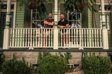 Feature shot of two men standing on a front porch.