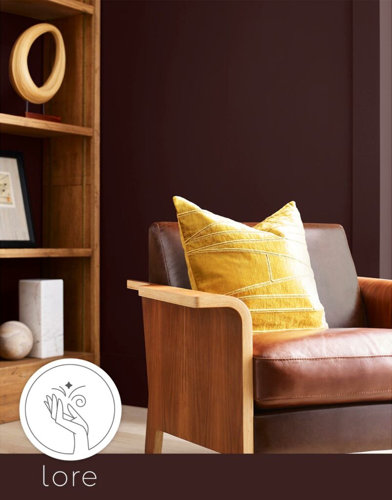A sitting area vignette with a leather chair with a yellow pillow on it and the Lore logo in the bottom left corner.