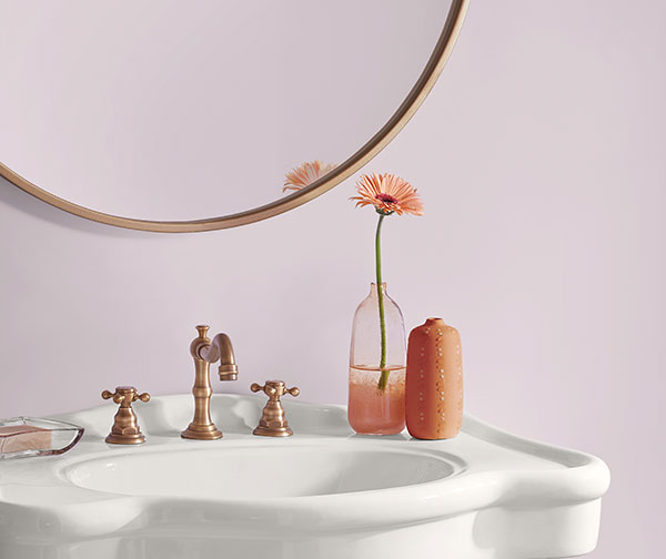 Detail image of a bathroom sink with a single flower stem in a small glass vase.