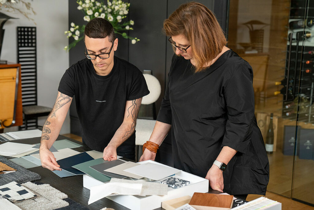 Sue Wadden and Christian Siriano standing at a table filled with peel and stick color samples.