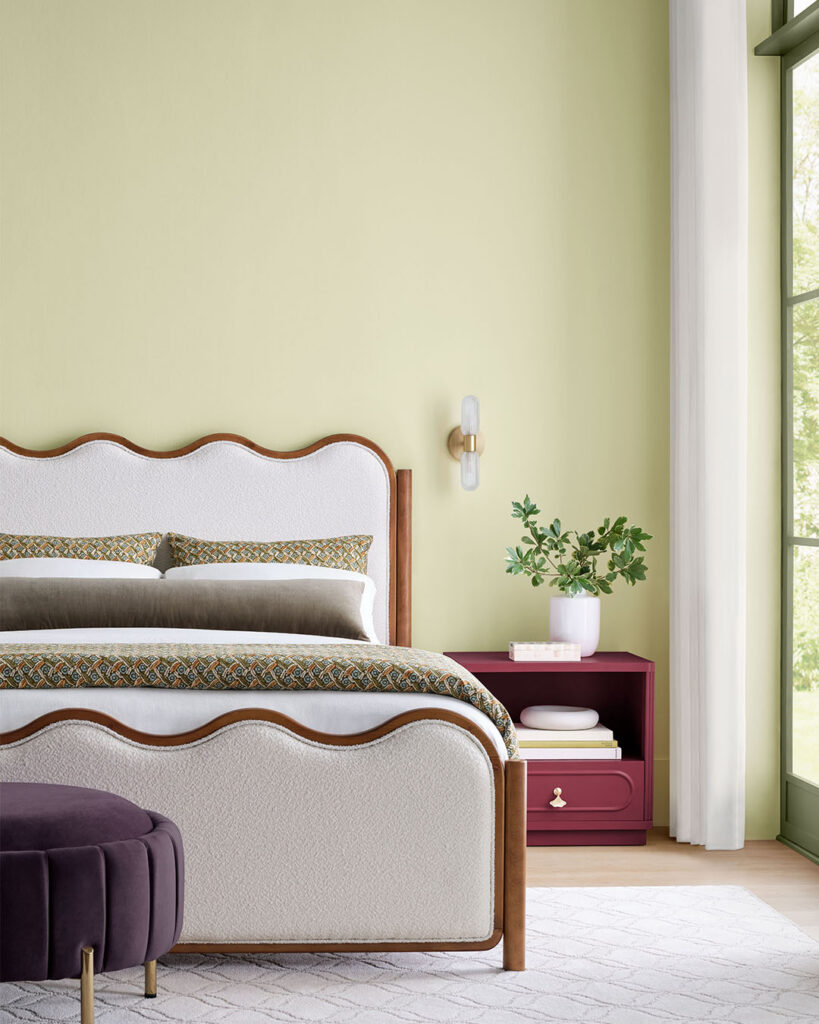 Bedroom scene with focus on a bed  and backdrop of Celery painted walls.