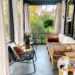 Front porch area with rattan seating and a fiddle leaf fig. Porch ceiling is painted in Urbane Bronze, a dark, earthy shade of gray-green.