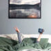 Blue bedroom wall with person in bed holding up peace sign.